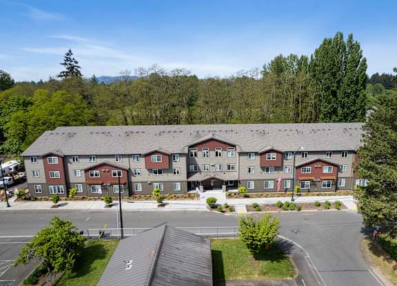 A large apartment complex with a parking lot in front.