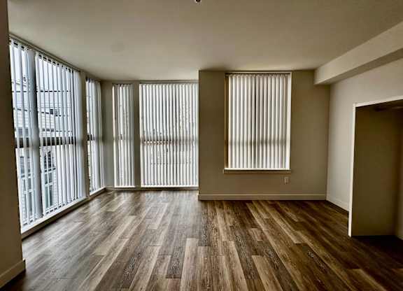 Large 1-bedroom living space at Bode-88 apartment homes with luxury vinyl plank floors and large windows with coverings