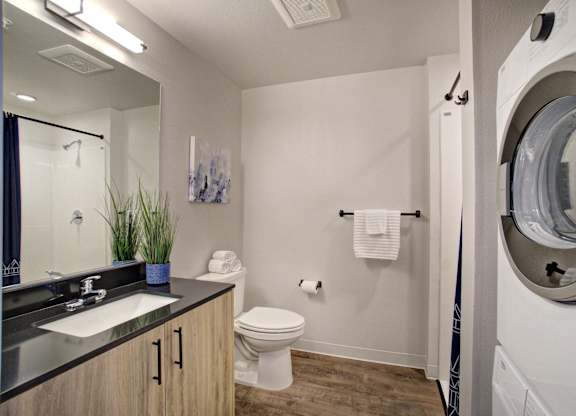 A bathroom with a toilet, sink, and mirror at The Hub Apartments, Lacey, 98503