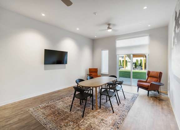 A room with a table and chairs and a television on the wall at The Hub Apartments, Washington