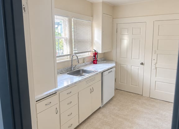 A kitchen with white cabinets and a window above the sink.
