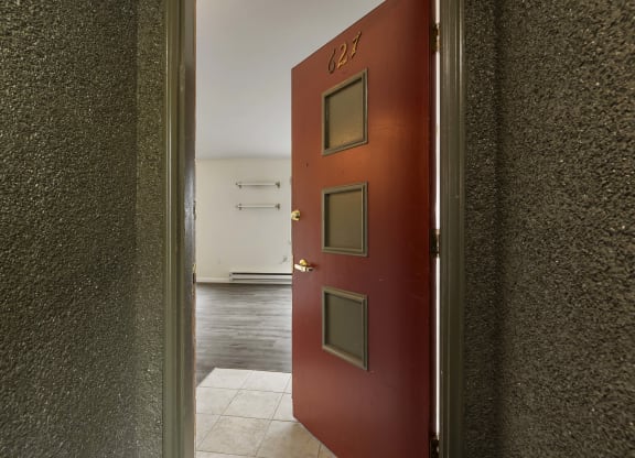 an open red door leading into a room with a hall way and a white floor