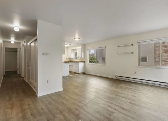 the living room and kitchen of an apartment with wood floors and white walls
