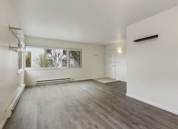 an empty living room with a large window and white walls