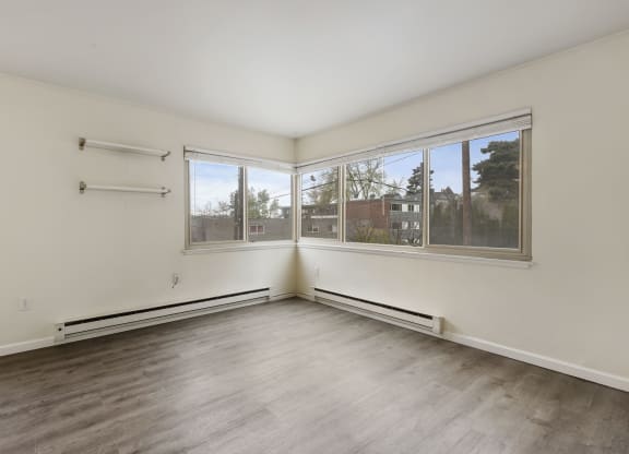 an empty living room with wood floors and large windows