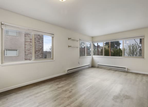 an empty living room with large windows and wood flooring