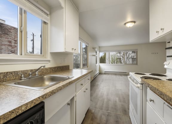 a kitchen with white cabinets and a sink and a window