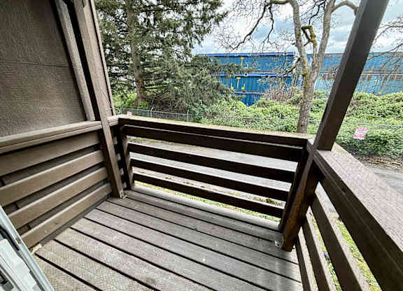 A wooden deck with a view of a blue container and trees.