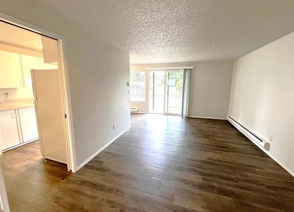A room with wooden flooring and a sliding glass door leading to a balcony.