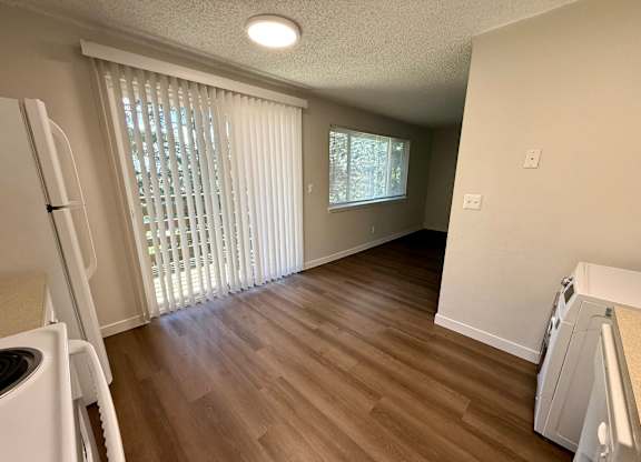 A kitchen with a white fridge and a window with blinds.