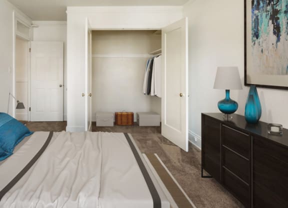 a bedroom with a white bed and blue pillows and a closet