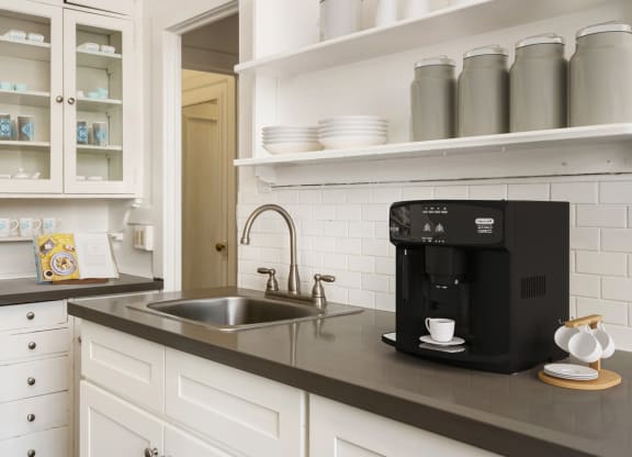 a kitchen with white cabinets and a black coffee maker on the counter