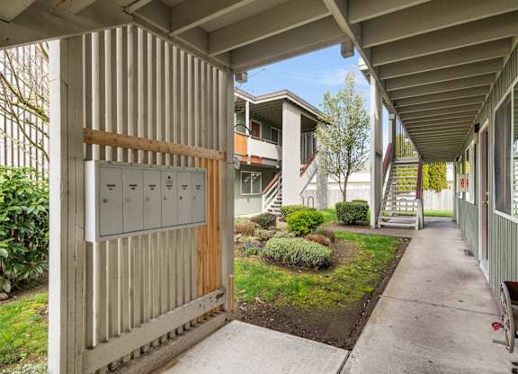 A corridor with a wooden gate and a metal mailbox.