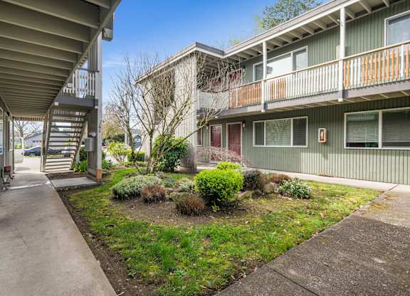 A concrete walkway leads to a building with a balcony.