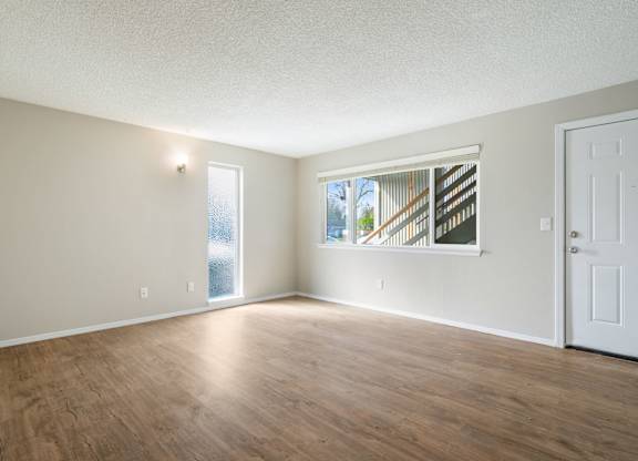 A room with wooden floors and a window showing a staircase outside.
