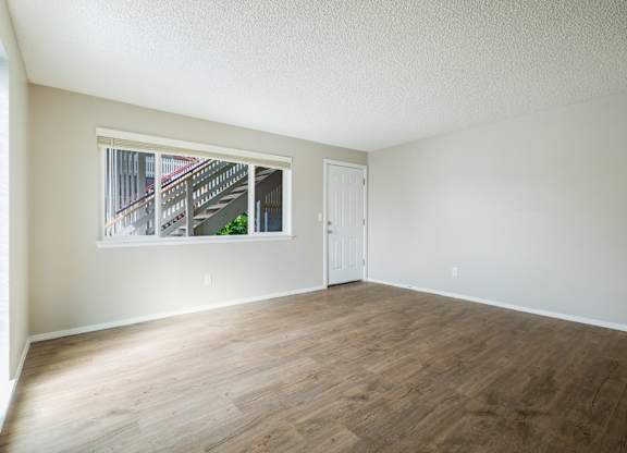 Empty room with wooden flooring and a window.