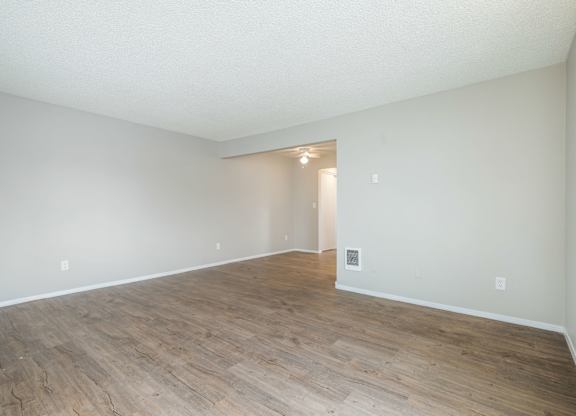 Empty room with wooden flooring and white walls.
