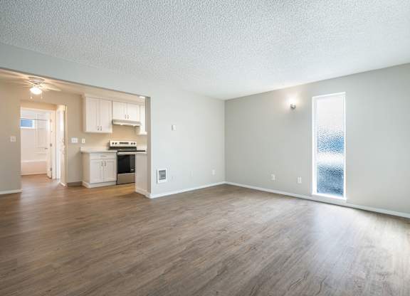 A large empty room with wooden floors and a window.