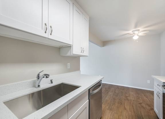 A kitchen with white cabinets and a stainless steel sink.