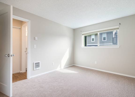 A room with a door, window, and carpeted floor.