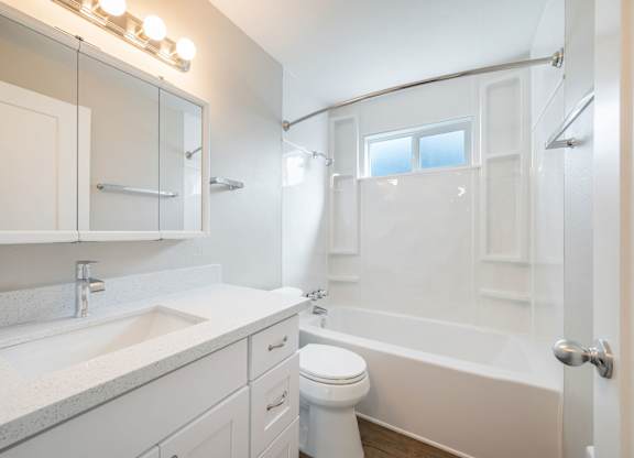 A white bathroom with a toilet, sink, and bathtub.