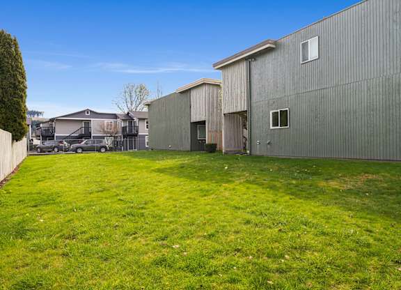 A large grassy yard with a building in the background.