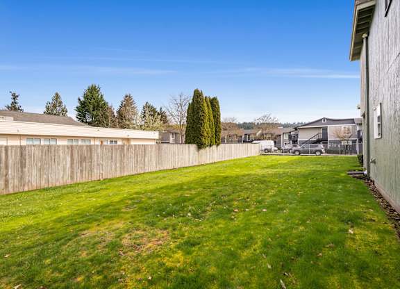 A backyard with a fence and a green lawn.