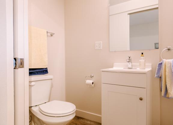A white toilet is in a bathroom with a white sink and a white cabinet.