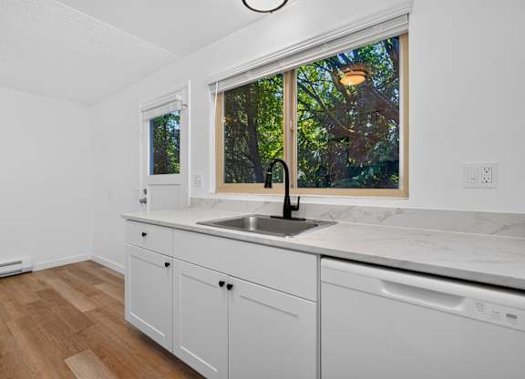 A kitchen with white cabinets and a marble countertop.