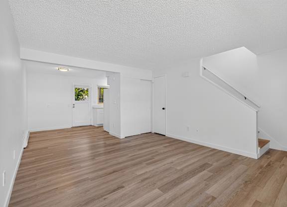 A room with wooden flooring and white walls.