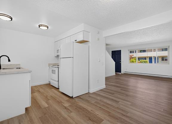 A kitchen with white appliances and wooden floors.