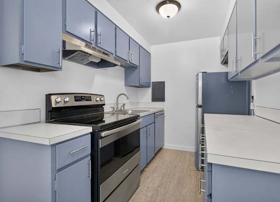 A kitchen with blue cabinets and white countertops.