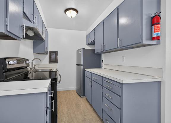 A kitchen with grey cabinets and a white counter.