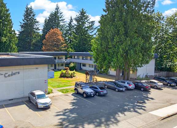 A parking lot with cars and a building with a sign that says "Cedars".