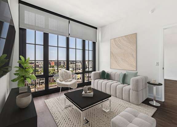 A living room with a large window and a view of the city.