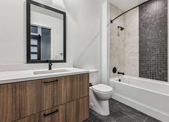 A white sink with a mirror above it and a white toilet next to a bathtub.