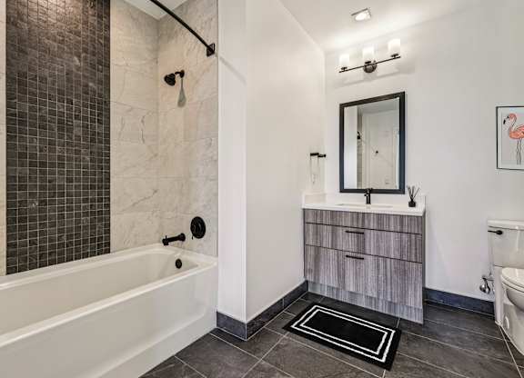 A bathroom with a white tub and a wooden vanity.
