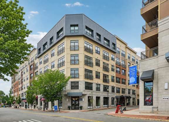 A street view of a multi-story building with a blue banner on the right side.