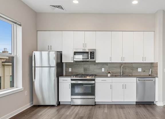 A modern kitchen with white cabinets and stainless steel appliances.