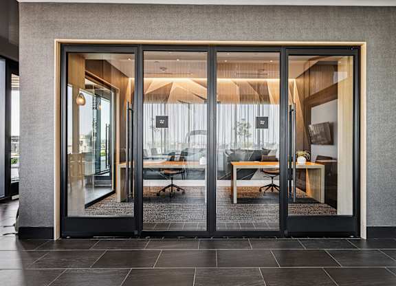 A modern office with glass doors leading to a meeting room.