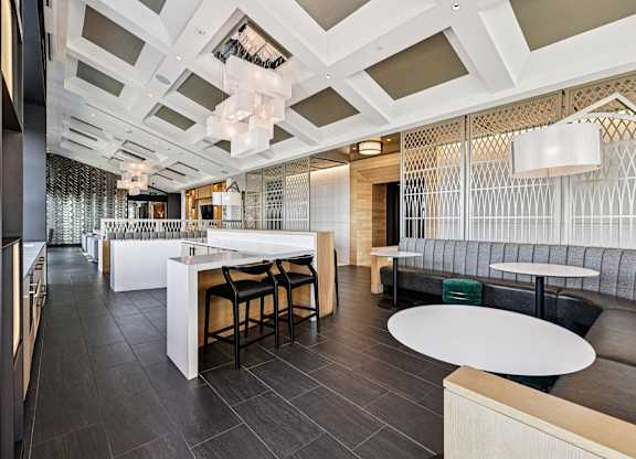A modern dining area with a white counter and black chairs.