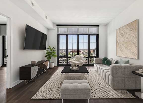 A living room with a large window, a flat screen TV, and a long couch.