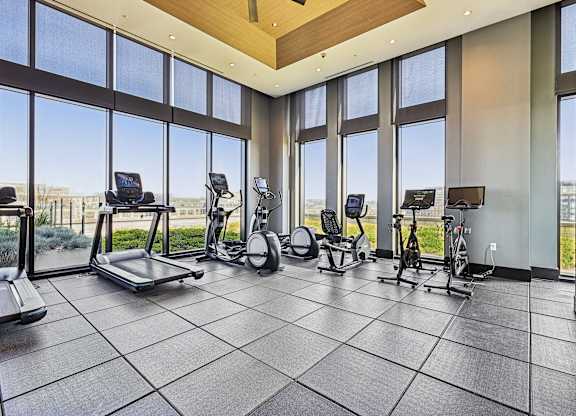 A spacious gym with treadmills, stationary bikes, and elliptical machines.