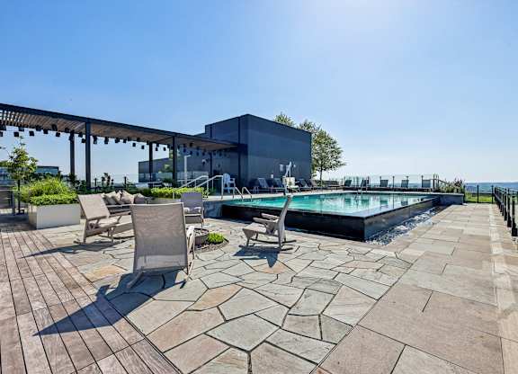 A pool area with a patio and chairs.