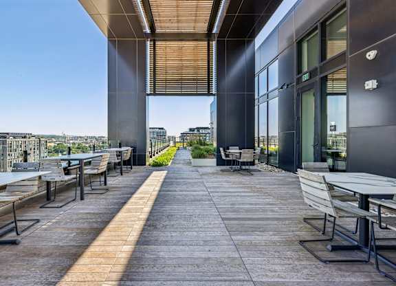 A patio with tables and chairs overlooking a cityscape.