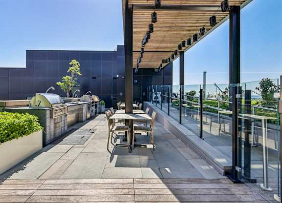 A modern outdoor seating area with a glass railing and a wooden pergola.