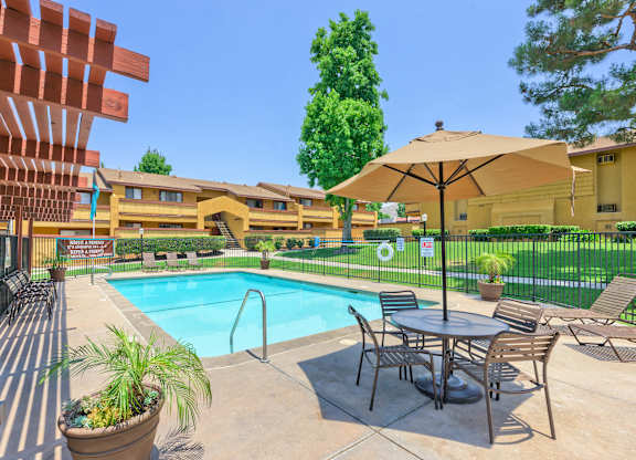 A pool area with a table and chairs and a patio umbrella.