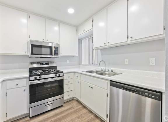 A modern kitchen with white cabinets and stainless steel appliances.