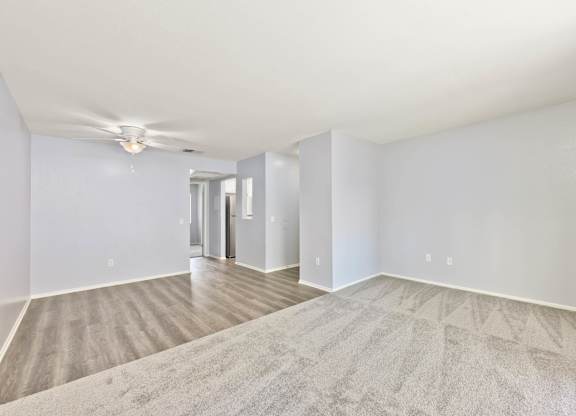 A spacious room with a carpeted floor and a ceiling fan.