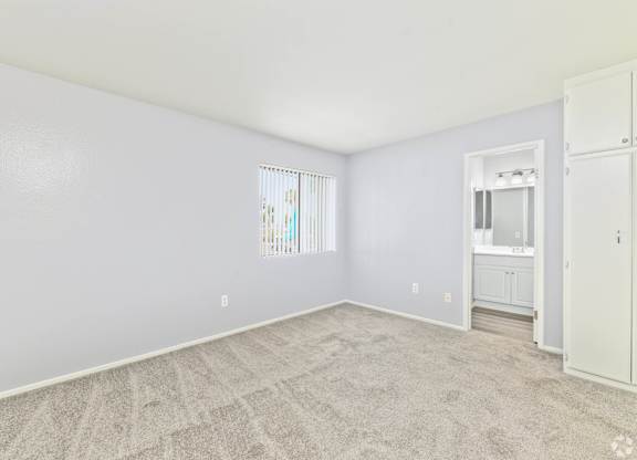 A white room with a carpeted floor and a window with blinds.